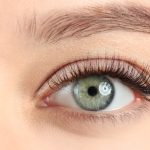 A woman's eyes, close up. The eyes are a gray-blue color and framed by neatly groomed lashes and brows.