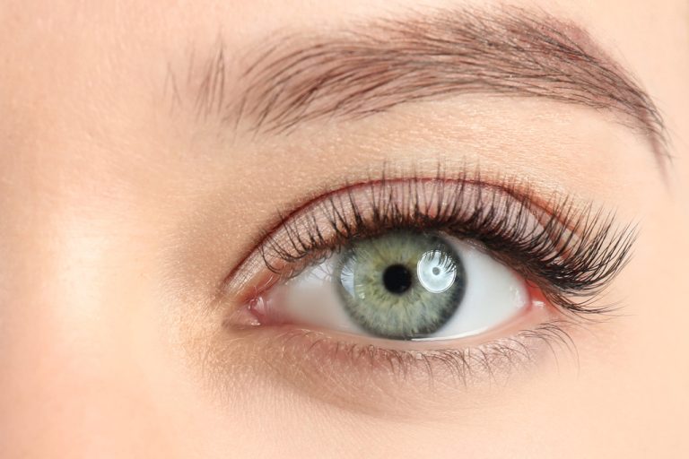 A woman's eyes, close up. The eyes are a gray-blue color and framed by neatly groomed lashes and brows.