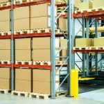 Several rows of sturdy metal storage racks are filled with pallets of boxes. Others are only at partial capacity.