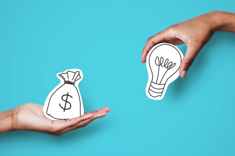 Two hands holding paper symbols of a bag of money and a lightbulb, against a teal background.