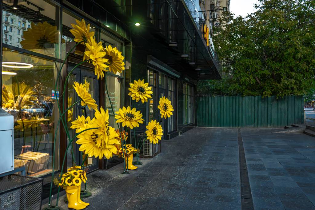 A welcoming, well-maintained storefront decorated with multiple arrangements of bright yellow sunflowers.