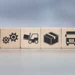 Eight small wooden blocks stacked next to each other. Each block has a different icon related to supply chain management.