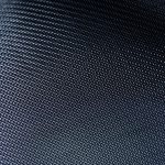 A close-up view shows a silver metal fabric lying on a dark-colored backdrop. The metal fabric creates a lattice weave.
