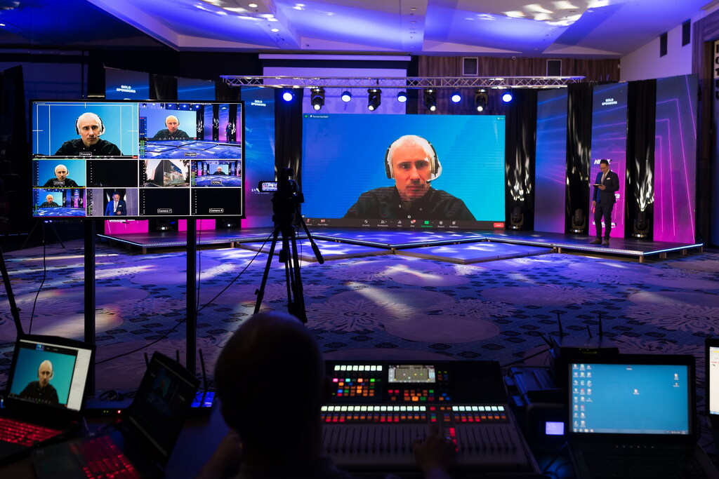 An event space with an online masterclass on multiple screens. The room is dimly lit with blue and pink lights.