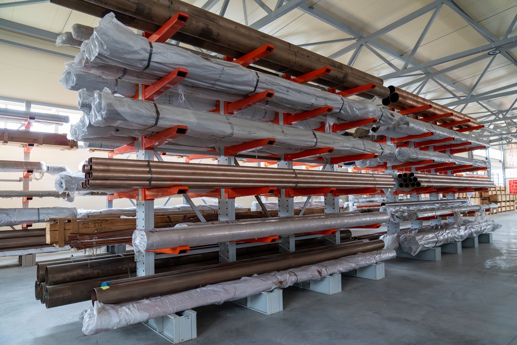 Cantilever racking holding different pipe materials. The material is in a covered part of the warehouse.