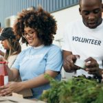 Group of volunteers packing food donations and supplies into boxes during a community charity event outdoors