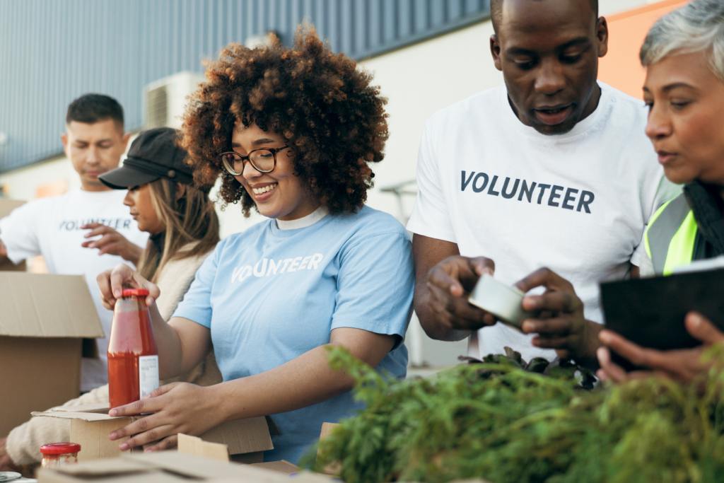 Group of volunteers packing food donations and supplies into boxes during a community charity event outdoors