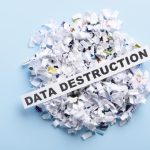 A pile of shredded pieces of paper are lying on a blue surface. On top of the pile is a sign that has text on it.