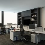 A modern open office with white desks, computer monitors, black mesh chairs, and built-in shelving on a wall.