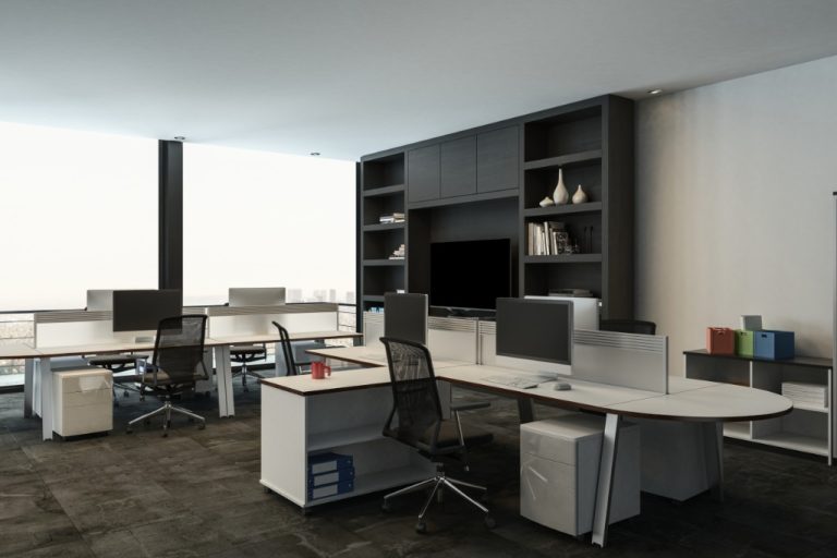 A modern open office with white desks, computer monitors, black mesh chairs, and built-in shelving on a wall.