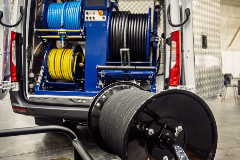 Professional drain-cleaning van interior with hose reels and tools neatly organized, ready for industrial plumbing work.
