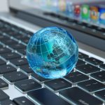 A globe icon sits on a laptop keyboard. The globe represents reliable internet connection and speeds.