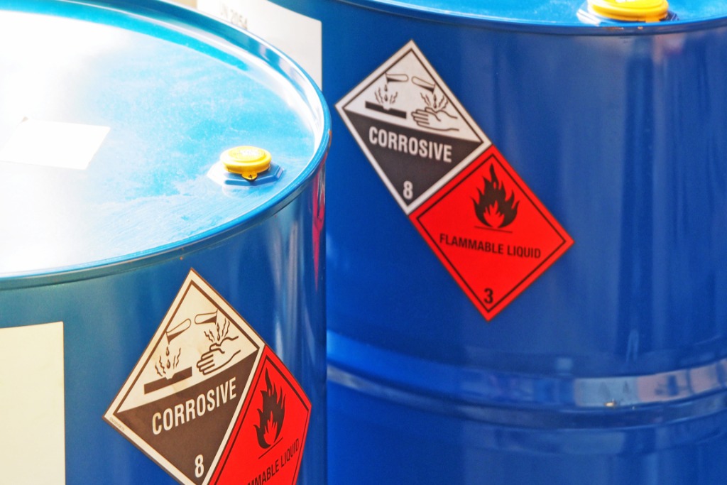 Two blue hazardous containment barrels. They have stickers on the side of them that say they are corrosive and flammable.