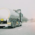 A truck is driving down a road away from the camera. There are no other cars on the road.