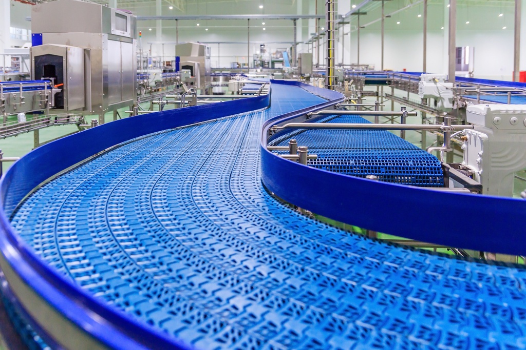 An empty blue conveyor belt with a plastic blue protection fence along the edge, inside a large warehouse.