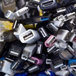 A large pile of different computer cables all jumbled together. There are USB cables and ports as well as ethernet.