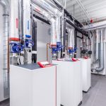 A behind the scenes look at a building's heating room. The system has three separate heat pumps and pipework.