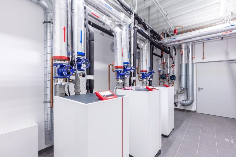 A behind the scenes look at a building's heating room. The system has three separate heat pumps and pipework.