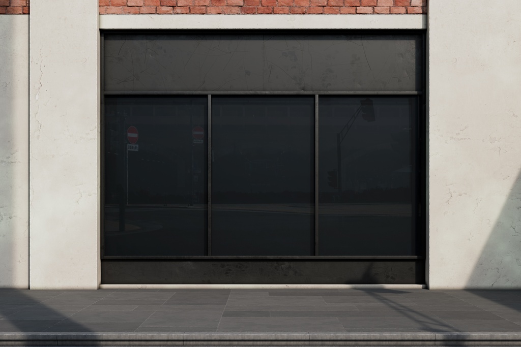 A storefront with dark glass windows, red brick above, light walls, a sidewalk, and shadows across the facade.